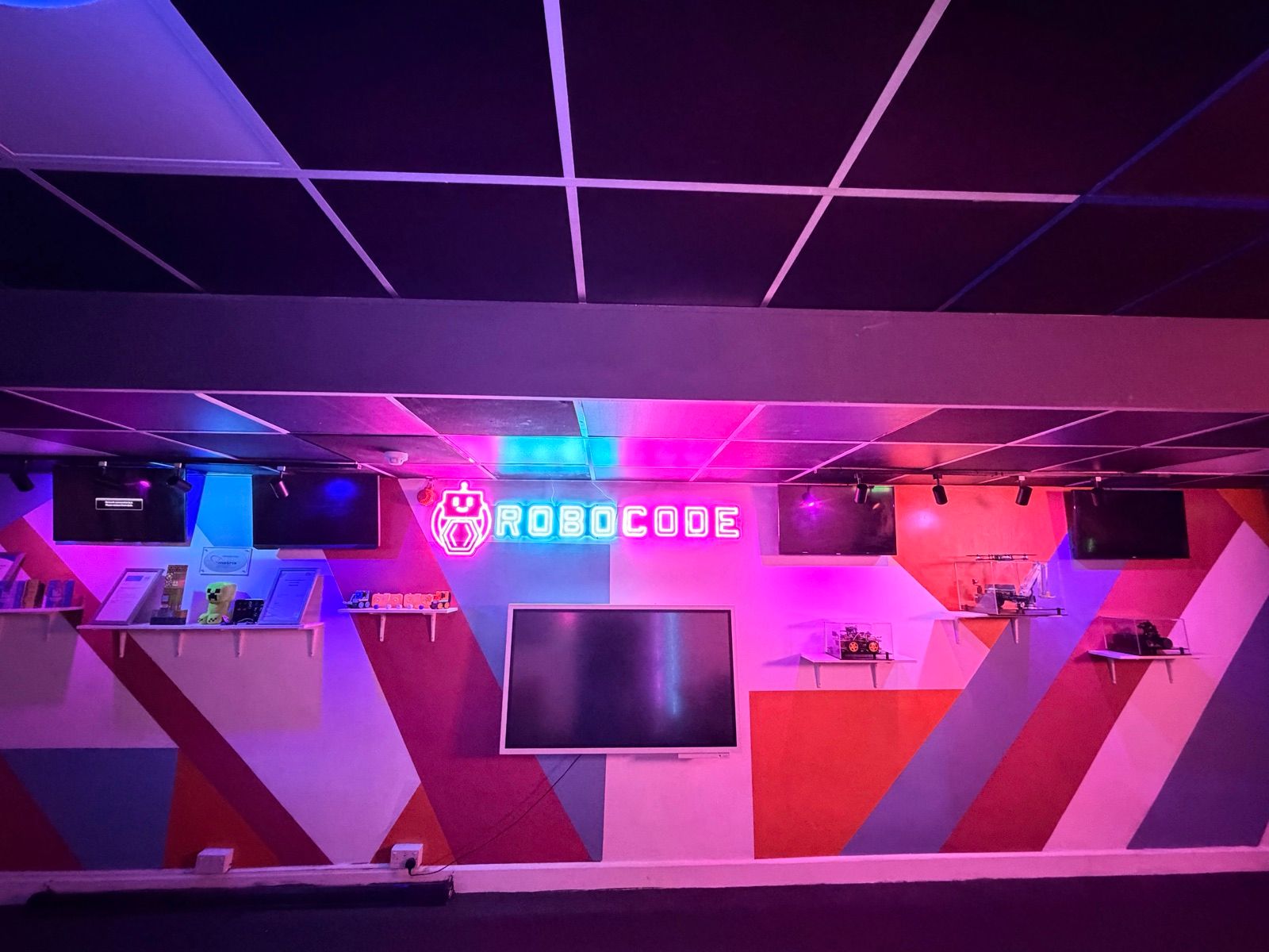 A Robocode centre's feature wall, with the neon logo over the display screen