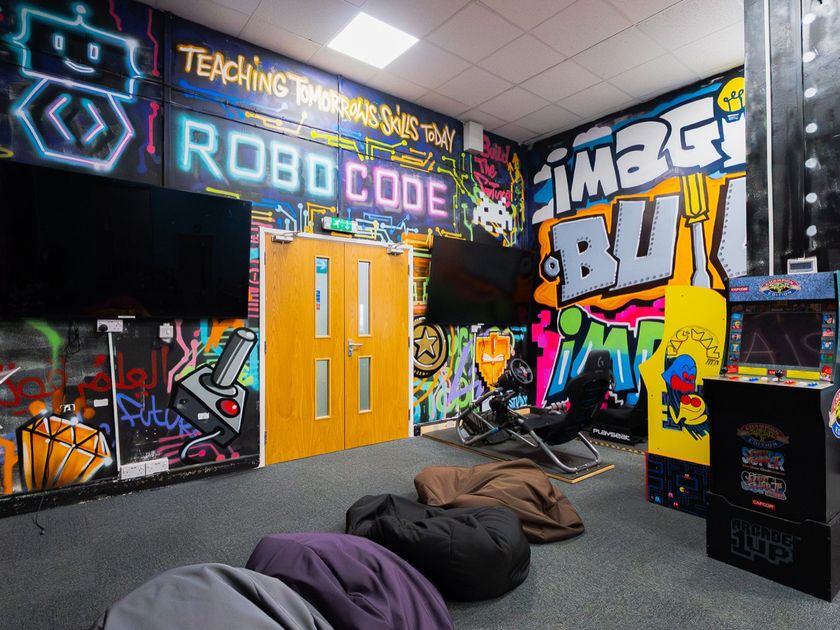 The arcade area with a graffiti mural, arcade machines and a racing simulator