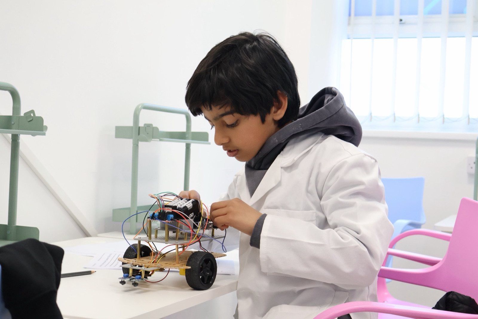 A Robocoder in a lab coat building a robot car