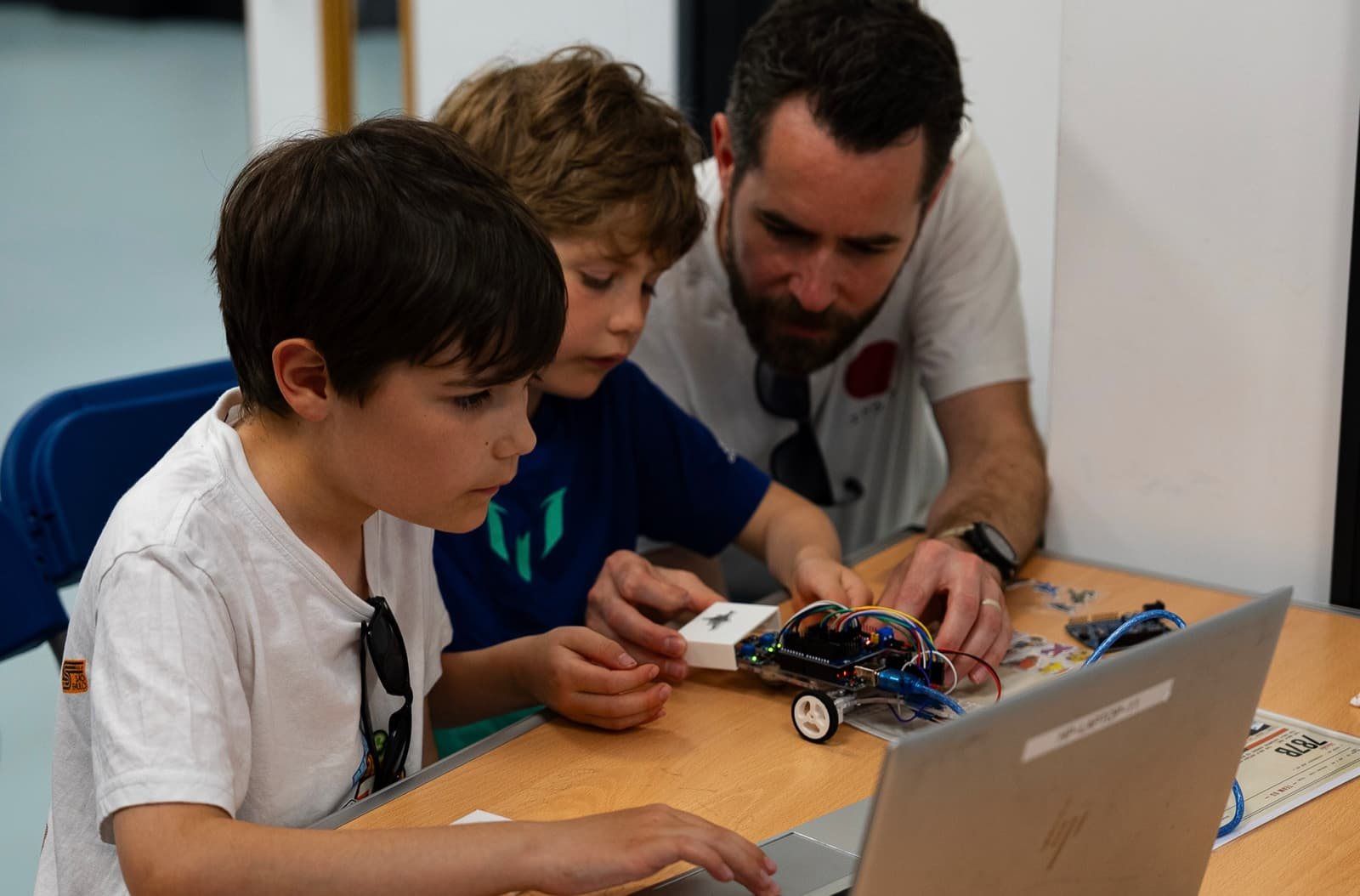 A Mentor helping two Robocoders build a robot car