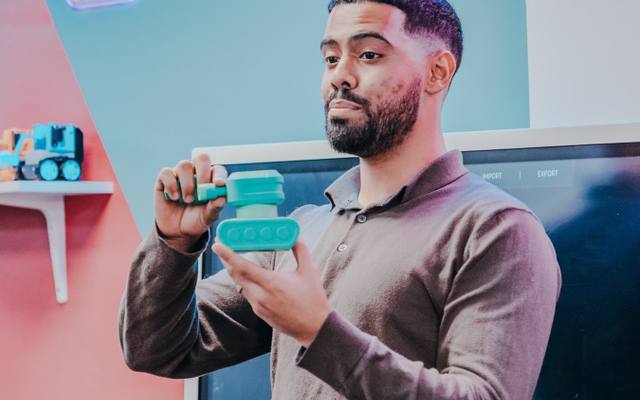 A Mentor holding up a part fresh from the 3D printer