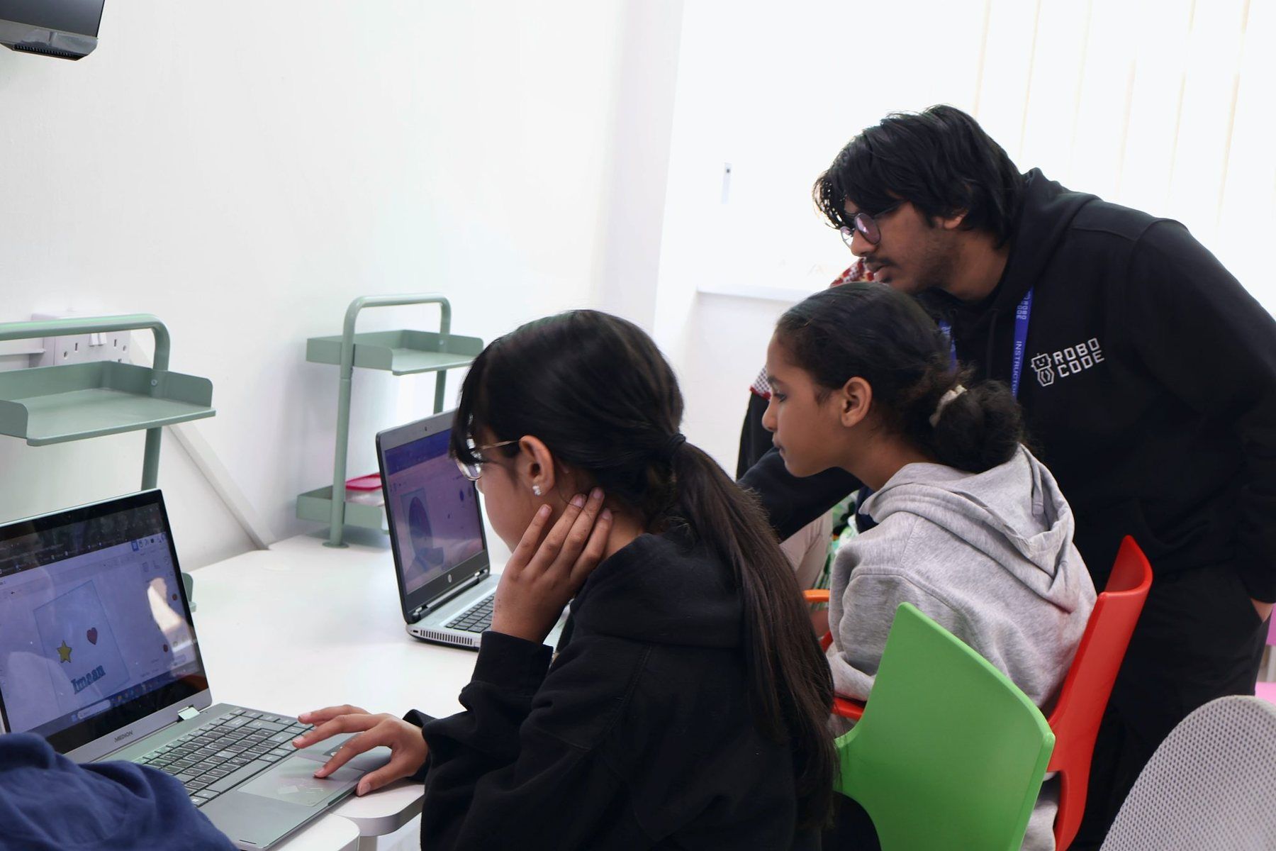 A Mentor working one to one with two Robocoders at their laptops