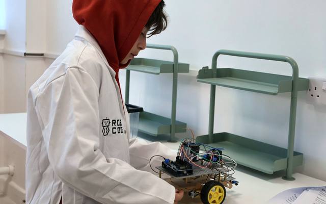A Robocoder in a lab coat building a robot car